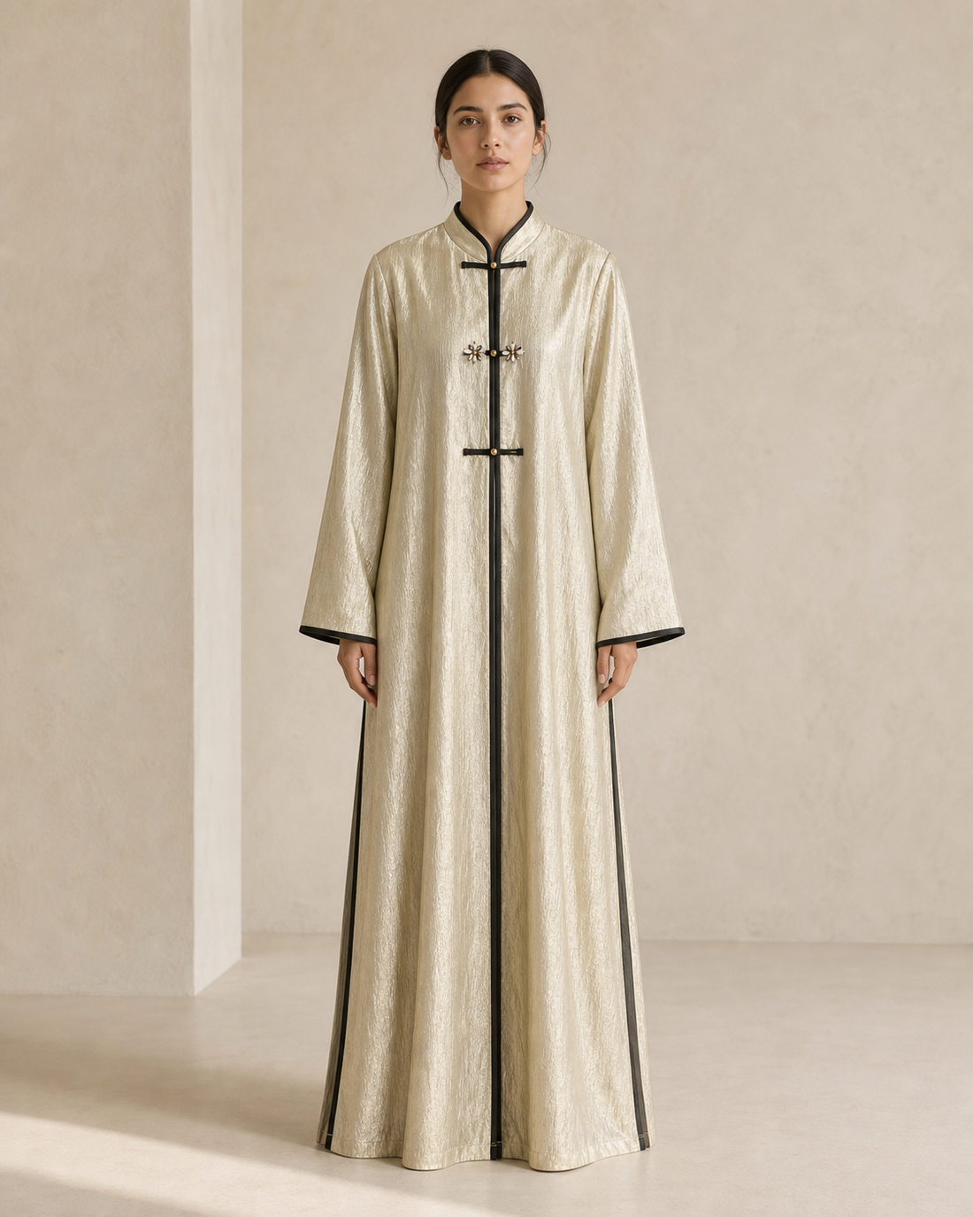 Model wearing a light gold full-length THENN abaya against a neutral studio background